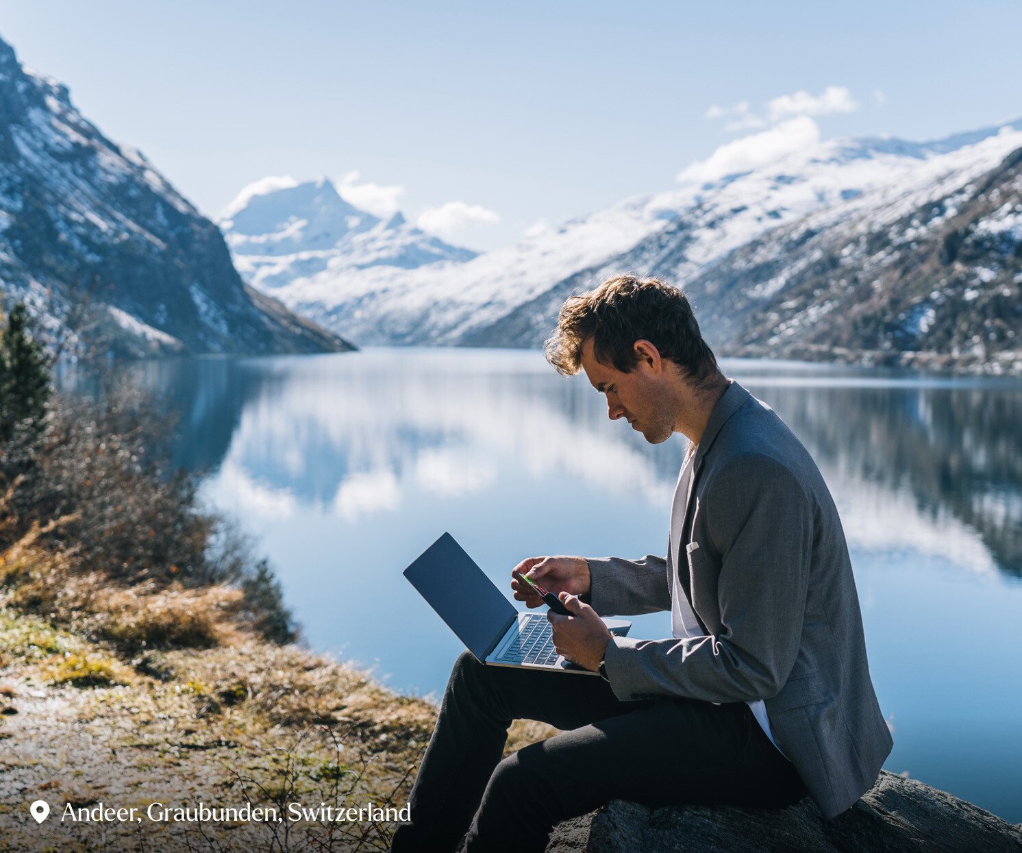 Business man relaxes by wintery mountain lake in the morning - stock photo