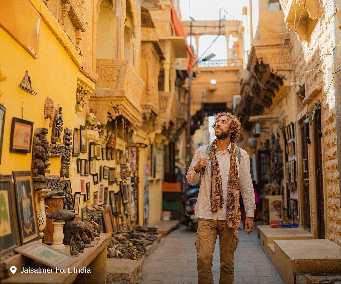 Man exploring Jaisalmer old town inside fort with gift shops and old architecture - stock photo