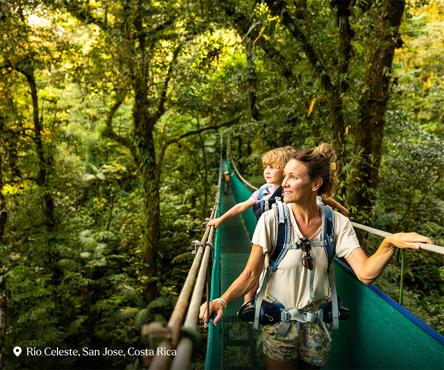 A family hiking across a suspension bridge in Costa Rica. - stock photo