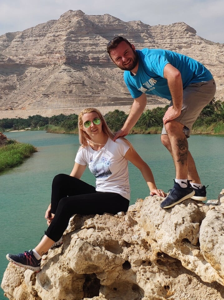 Image of a young man and a woman standing on a mountain with a picturesque background