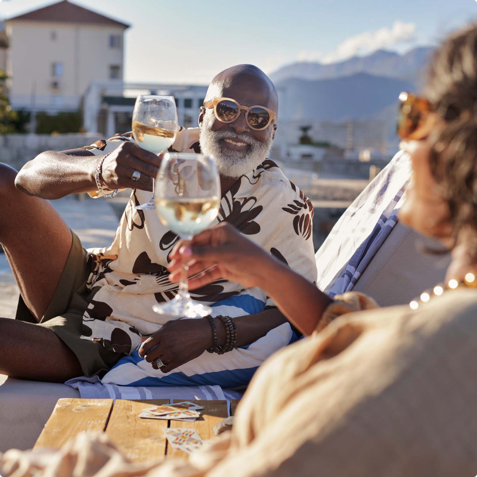 A man and woman on holiday holding up their glasses of wine to cheers